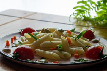 delicious pasta, served with small tomatoes on wooden table, close-up photo and light background