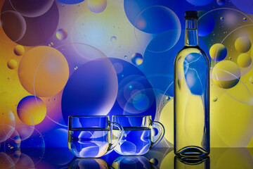 transparent glass cups with water, bottle and oil drops on colorful background
