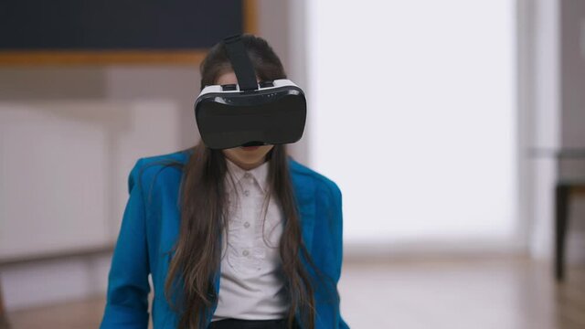 Portrait of scared teenage girl in VR headset playing video game. Frightened Caucasian teenager gaming in augmented reality at home indoors on weekend. Leisure and lifestyle