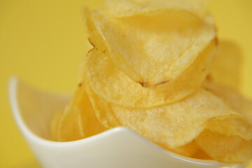 Naklejka na ściany i meble Potato chips. chips close-up in ceramic cup on bright yellow background.Chipsy. Fast food and snack.