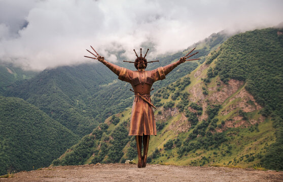 VERKHNIY ZGID, RUSSIA - 07 25 2021: Newly built Dance With Daggers monument towering along with high mountain peaks in Verkhny Zgid village. Monument celebrates ancient culture of Ossetians, native