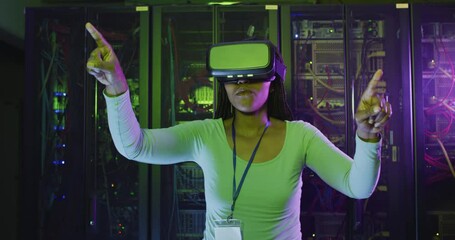 African american female computer technician using vr headset working in business server room - Powered by Adobe