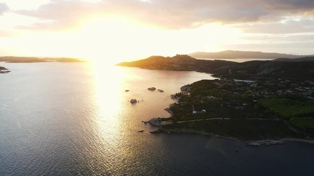 drone flying over the old town of Palau. Charming small city on the coast. romatic warm light from sunrise. aerial view sideways, Italy