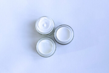 Three jars of cosmetic greasy cream, isolated on a white background. Top view. Cosmetic products.