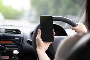 A woman driving a car on a highway road. Hand holding a black touch screen mobile phone. Smartphone...