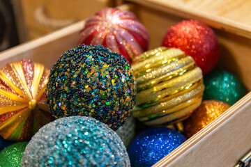Beautiful multi-colored Christmas balls lie in a wooden box. Preparing for the new year and christmas. Large shiny balls.