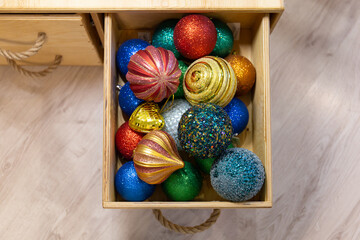 Beautiful multi-colored Christmas balls lie in a wooden box. Preparing for the new year and christmas. Large shiny balls.