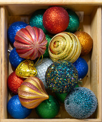 Beautiful multi-colored Christmas balls lie in a wooden box. Preparing for the new year and christmas. Large shiny balls.