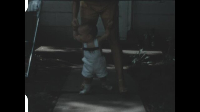 Toddler Walking 1952 - A baby takes his first steps with the supervision of his mother. 