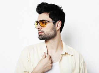 Elegant young handsome man in smart casual wear and sunglasses. Studio fashion portrait