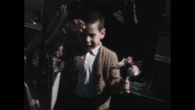 Holding Flowers 1956 - A young boy holds flowers in front of a car.