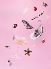 Flying oysters, glass of wine and christmas balls on a pink background. Festive Christmas or New...