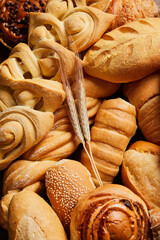 Close up of different types of breads and golden buns with ears of wheat. Food and bakery concept....