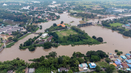 Flood waters overtake a house and rice field at Central of Thailand in 2021. Many buildings are submerged in water. Photo disaster from above view by drone
