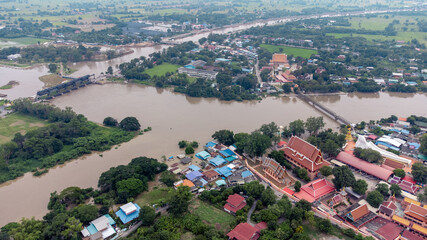 Fototapeta premium Flood waters overtake a house and rice field at Central of Thailand in 2021. Many buildings are submerged in water. Photo disaster from above view by drone