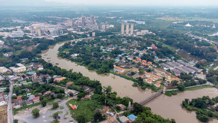 Flood waters overtake a house and rice field at Central of Thailand in 2021. Many buildings are submerged in water. Photo disaster from above view by drone