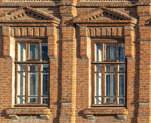 Two windows of the old mansion 19 century with brown bricks wall