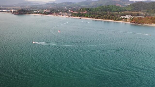 Parasailing during  at Langkawi island, Malaysia. white sandy beach and amazing sea on the background. Summer sunset seascape