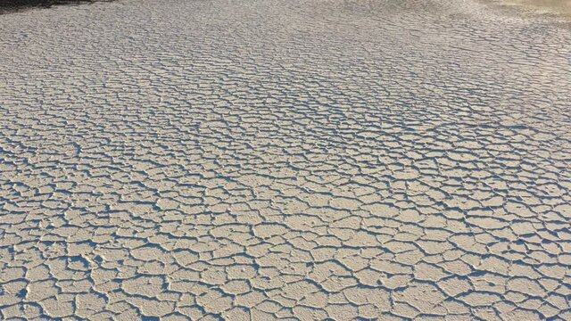 Dry salt flats at Badwater basin of Death valley national park during harsh sunlight.