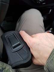 A man holding a pistol in a holster in his hand