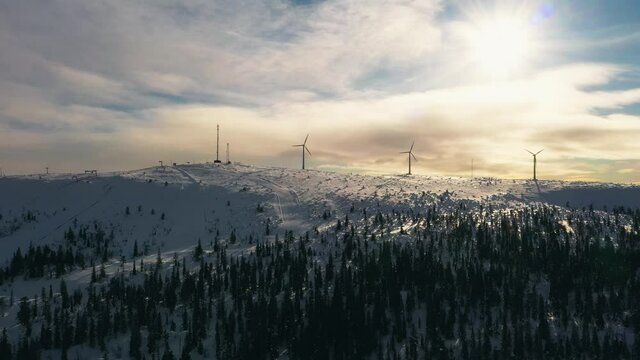 Aerial view of windmills rotating in heavy wind, top of snowy fells of Lapland - tracking, drone shot
