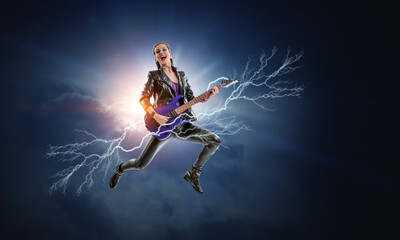 Obraz premium Young and beautiful rock girl playing the electric guitar