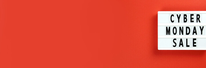 Cyber Monday sale text on lightbox on a red background. Creative top view flat lay promotion composition. Horizontal long banner for web design with copy space