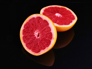 Fresh grapefruit cut in half on dark background.