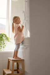 Little girl in the bathroom brushing her teeth