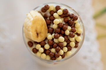 top view of a dairy dessert with banana and chocolate chips in a glass