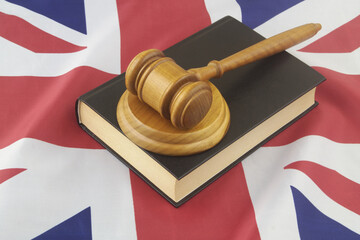 Wooden judge gavel with legal book on UK flag. United Kingdom court  concept.
