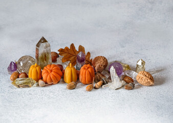 crystal minerals, pumpkins, autumn leaves, nuts on grey background. autumn composition. symbol of...
