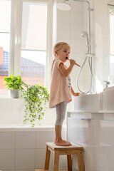 Little girl in the bathroom brushing her teeth