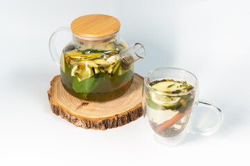 Moroccan tea in a transparent teapot on a white background next to a filled transparent mug