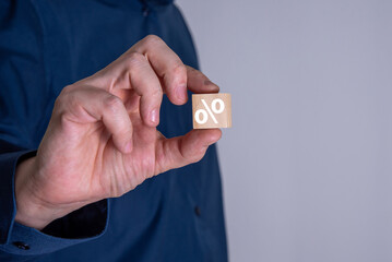 Businessman shows a wooden cube with a percent or percentage symbol.