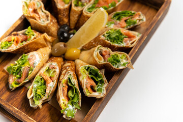 Pancakes with salmon and cottage cheese in wooden dishes on a white background close up