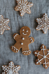 Christmas gingerbread man and snowflakes cookies on neutral linen cloth background. Flat lay, top view
