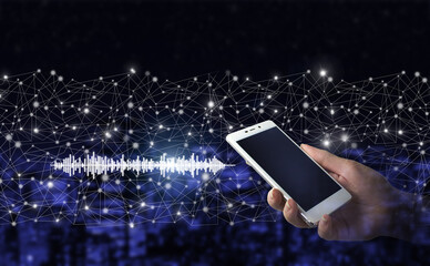 Hand hold white smartphone with digital hologram sound track, wave sign on city dark blurred background. Listening to music on mobile devices. Voice recognition.