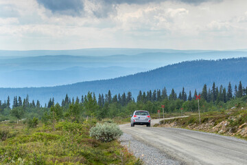 Fototapeta premium Car driving on a dirt road in a high country landscape