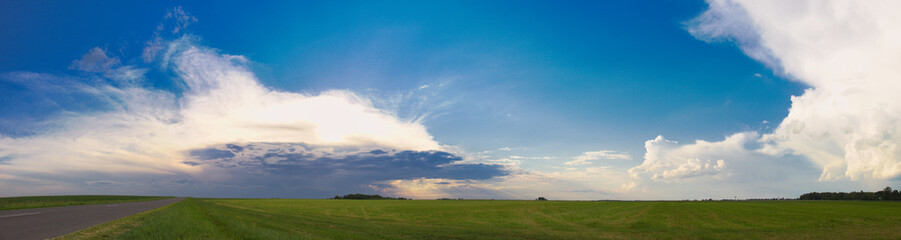 Obraz na płótnie Canvas beautiful white clouds over a green field