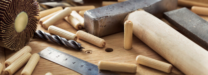 drill bit, hammer, dowel and rasp on wooden oak board