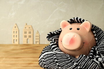 Concept of heating season with piggy bank on wooden table