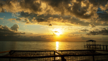 Obraz premium the rising sun shines through the clouds, sunny path on the water, calm sea and an empty beach