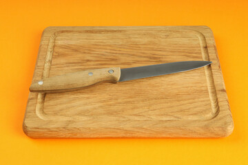 Cutting board with knife on orange background