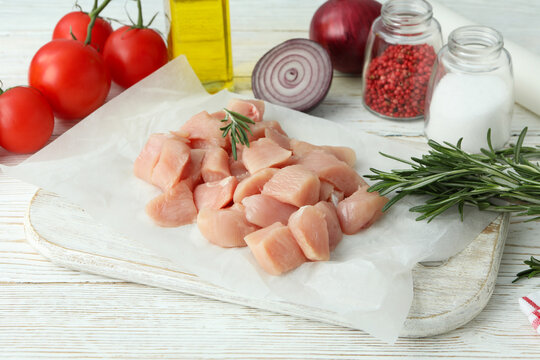 Concept of tasty food with slices of raw chicken fillet on white wooden background