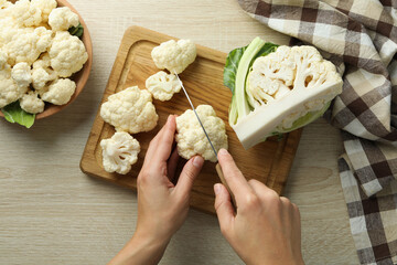 Female hands cut cauliflower on wooden board