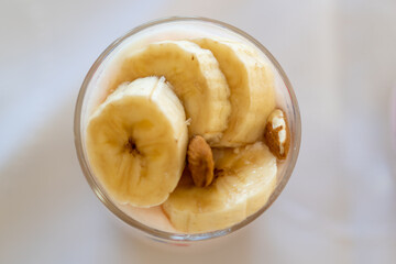 top view of a dairy dessert with banana, almond in a glass.