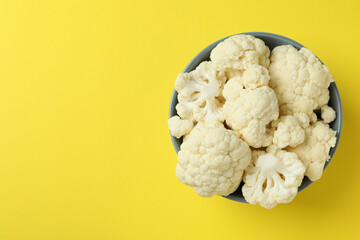 Fresh juicy cauliflower slices in bowl on yellow background