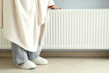 Concept of heating season with girl standing near radiator