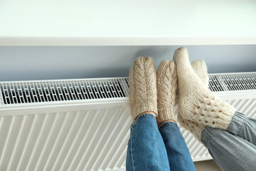 Concept of heating season with legs in knitted boots on radiator